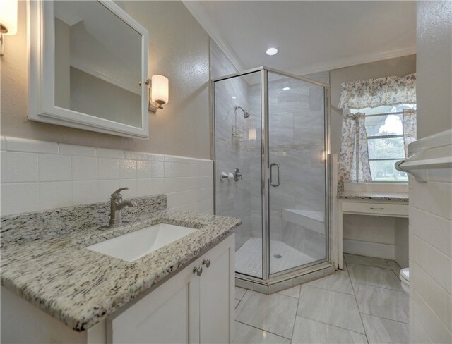 bathroom featuring toilet, tile walls, ornamental molding, vanity, and a shower with shower door