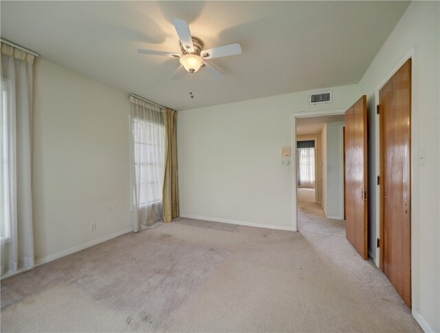 unfurnished room featuring light carpet, ceiling fan, and plenty of natural light