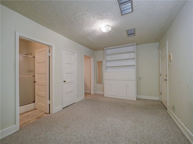 unfurnished bedroom with a textured ceiling and light carpet