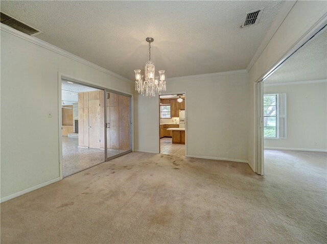 unfurnished dining area with ceiling fan, a textured ceiling, light carpet, and ornamental molding