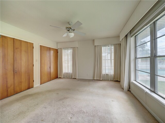 carpeted spare room featuring ceiling fan and plenty of natural light