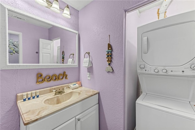 bathroom with stacked washer / drying machine and vanity