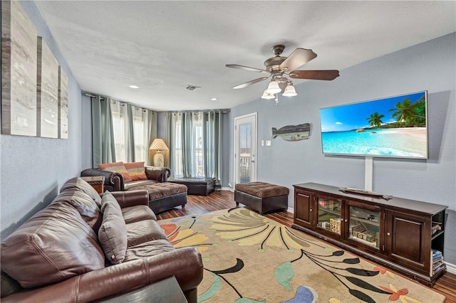 living room with hardwood / wood-style flooring, a textured ceiling, and ceiling fan