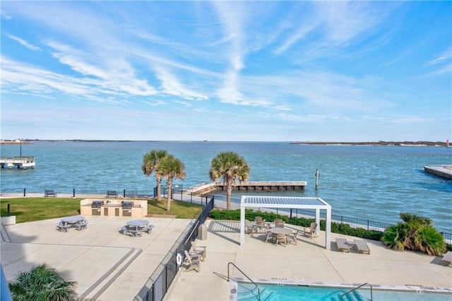 view of pool featuring a patio area, area for grilling, a pergola, and a water view