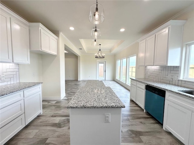 kitchen with a kitchen island, white cabinets, backsplash, dishwasher, and a raised ceiling