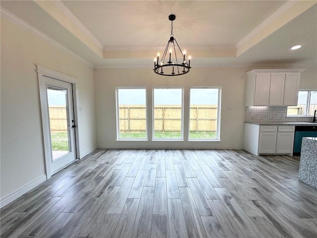 unfurnished dining area featuring a wealth of natural light, a tray ceiling, and wood finished floors