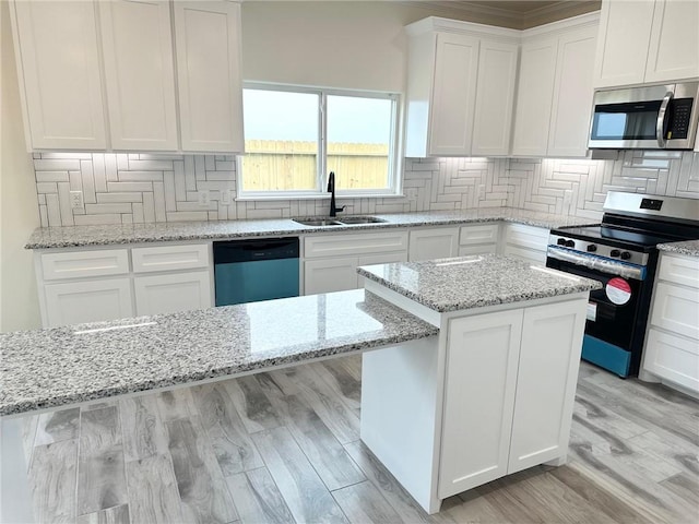 kitchen with light wood finished floors, tasteful backsplash, stainless steel appliances, white cabinetry, and a sink