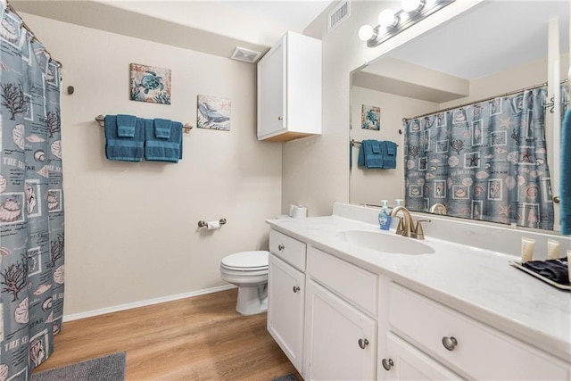 full bath with toilet, vanity, wood finished floors, and visible vents