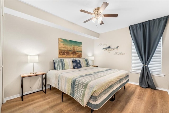 bedroom featuring ceiling fan, baseboards, and wood finished floors