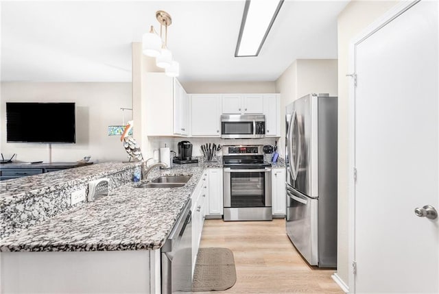 kitchen with appliances with stainless steel finishes, a sink, white cabinetry, and light stone countertops