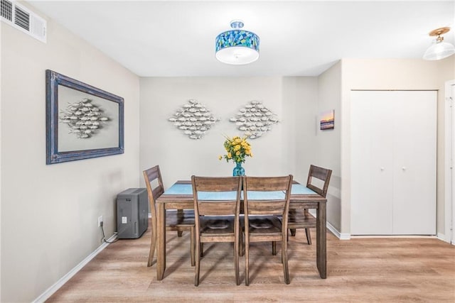 dining room with light wood-style floors, visible vents, and baseboards