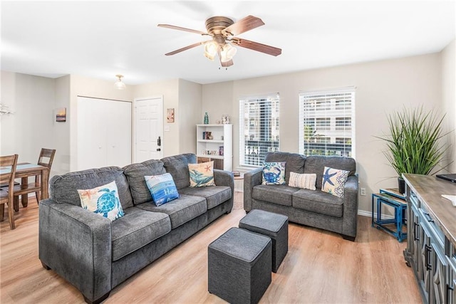 living room featuring light wood-type flooring, ceiling fan, and baseboards