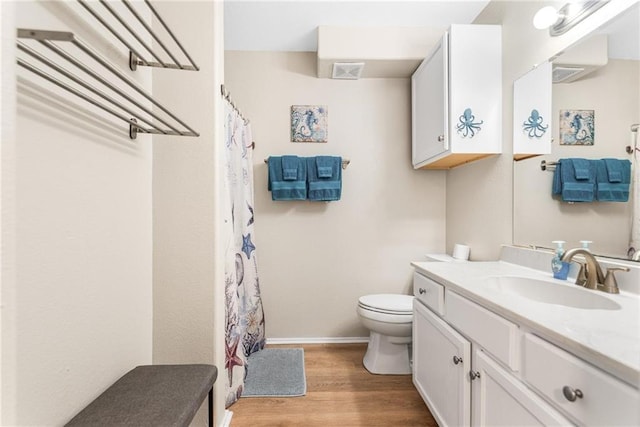 bathroom with baseboards, visible vents, toilet, wood finished floors, and vanity