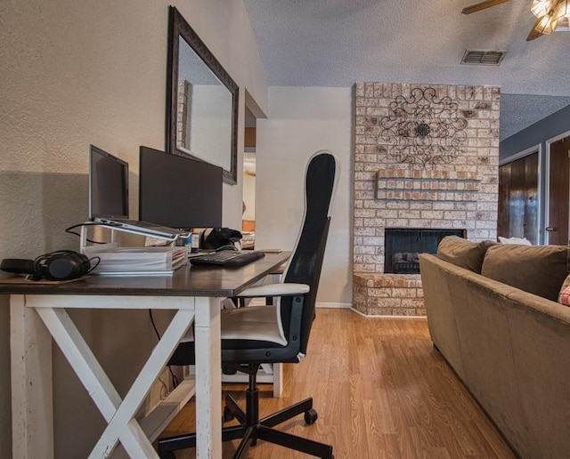2850 Tuscarora Dr, Corpus Christi, TX 78410 - office area with a textured ceiling, a brick fireplace, wood finished floors, a textured wall, and ceiling fan