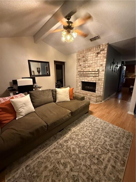 living room with a textured ceiling, visible vents, ceiling fan, wood finished floors, and vaulted ceiling with beams