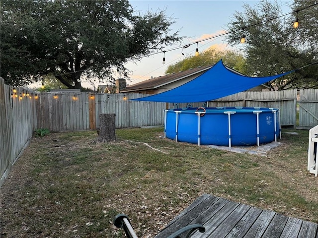 yard at dusk featuring a fenced in pool