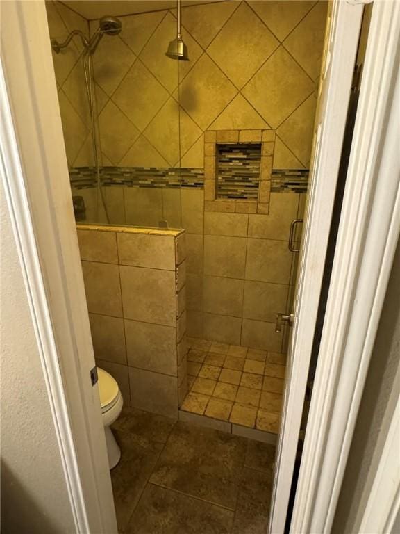 bathroom featuring tile patterned floors, toilet, and tiled shower