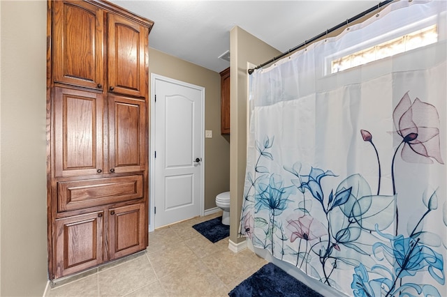 bathroom with tile patterned floors, walk in shower, and toilet