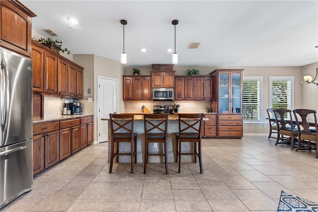 kitchen with backsplash, a breakfast bar area, decorative light fixtures, a kitchen island, and stainless steel appliances