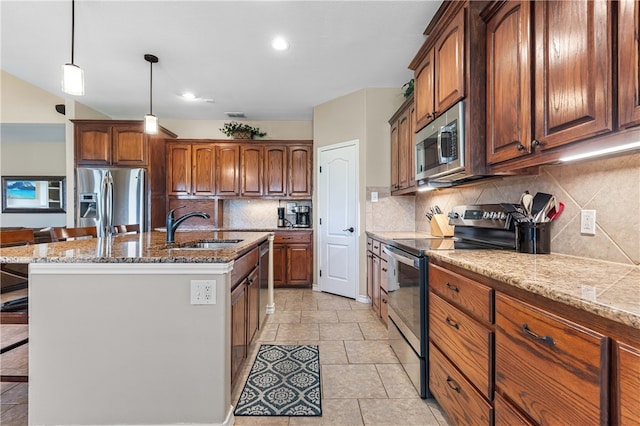 kitchen with decorative backsplash, appliances with stainless steel finishes, a breakfast bar, and an island with sink