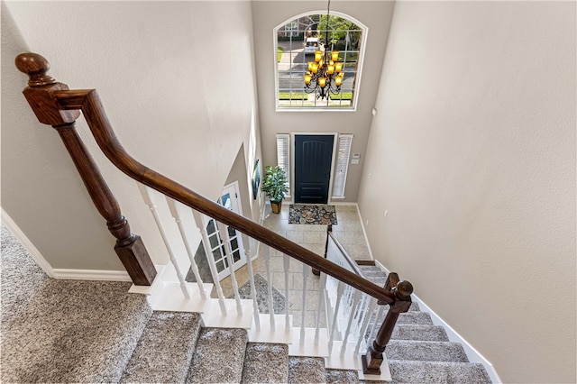 stairway featuring a chandelier, carpet, and a towering ceiling