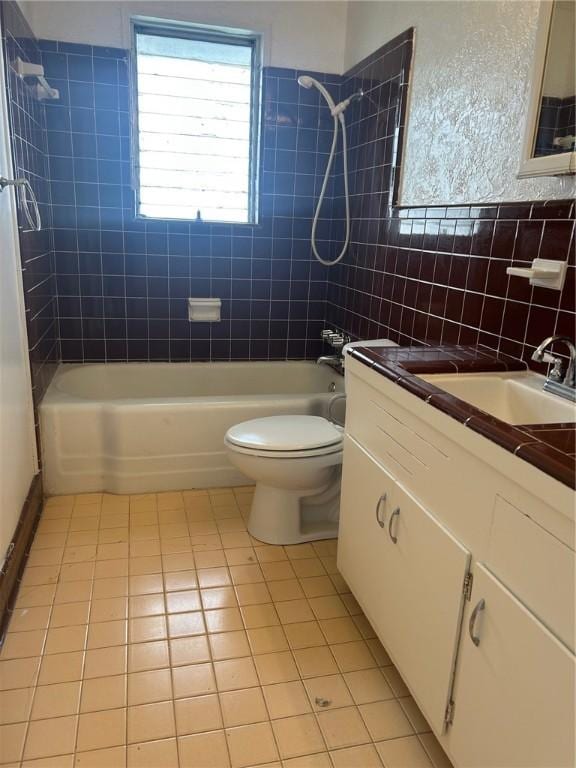 full bathroom with tiled shower / bath, tile walls, tile patterned flooring, vanity, and toilet