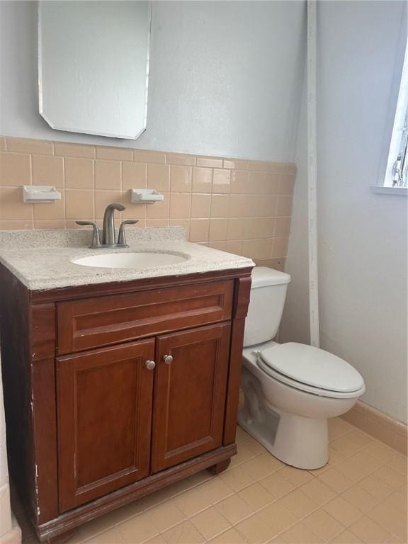 bathroom with vanity, tile walls, and toilet