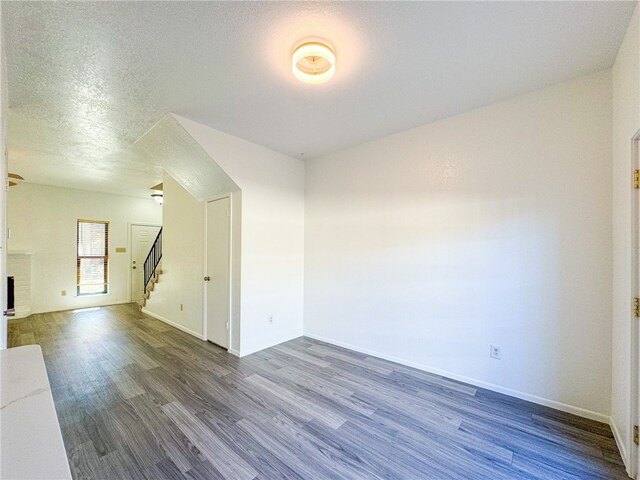 empty room featuring a textured ceiling, dark hardwood / wood-style floors, and a fireplace