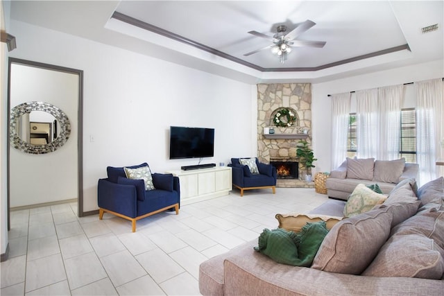 7002 Madiera Dr, Corpus Christi, TX 78414 - living room featuring a tray ceiling, a stone fireplace, ceiling fan, and light tile patterned flooring