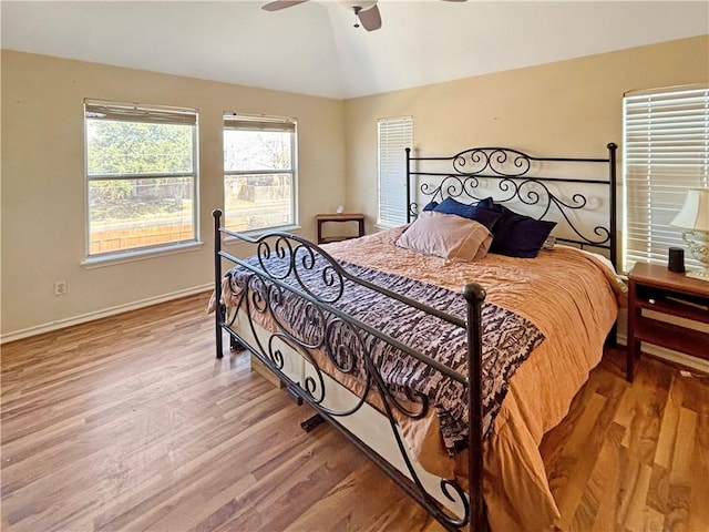 bedroom featuring ceiling fan, baseboards, light wood-style flooring, and vaulted ceiling