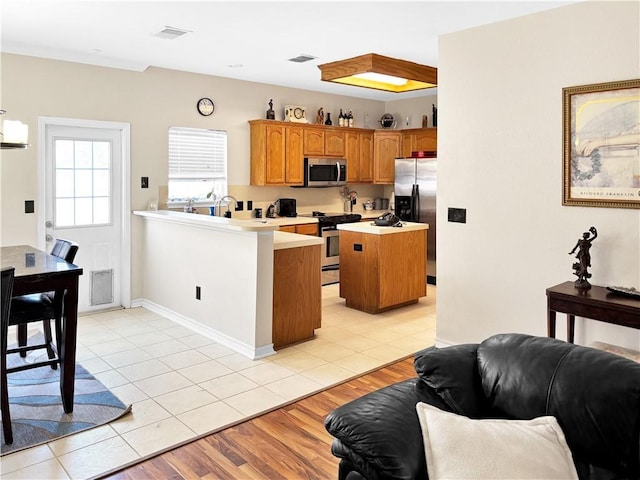 kitchen featuring visible vents, a peninsula, light countertops, appliances with stainless steel finishes, and open floor plan