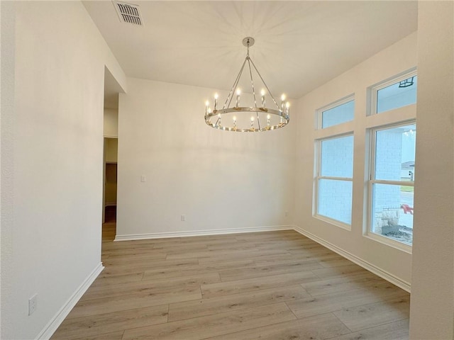 unfurnished room featuring light wood-type flooring and a notable chandelier