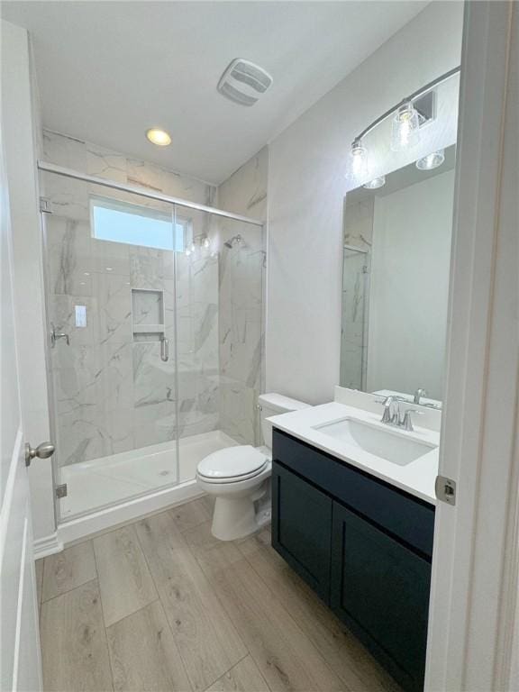 bathroom featuring a shower with door, vanity, wood-type flooring, and toilet