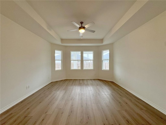 unfurnished room with ceiling fan, light hardwood / wood-style floors, and a raised ceiling