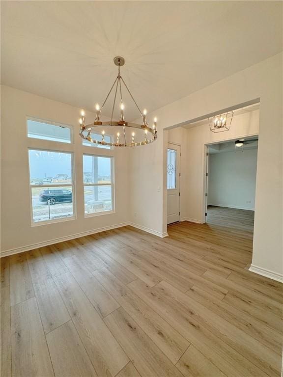 unfurnished dining area with light hardwood / wood-style flooring and a notable chandelier