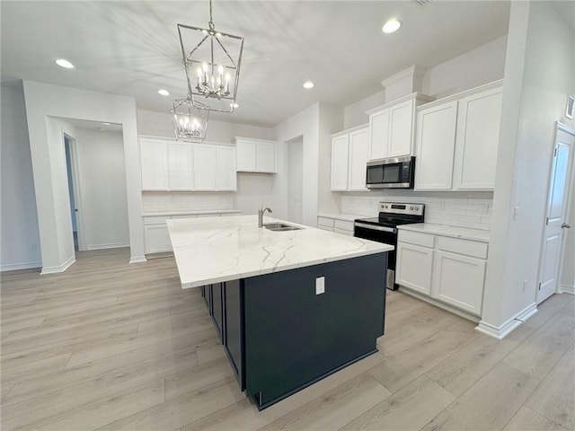 kitchen with stainless steel appliances, sink, white cabinetry, hanging light fixtures, and an island with sink