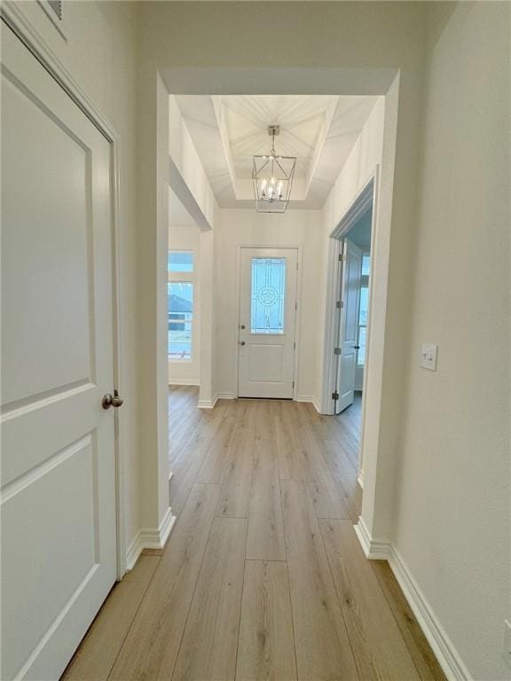 doorway to outside featuring light hardwood / wood-style flooring, beamed ceiling, and an inviting chandelier