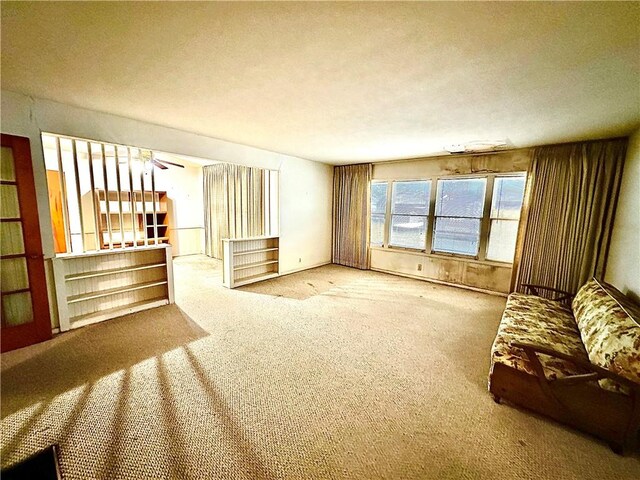 unfurnished living room featuring ceiling fan and carpet floors