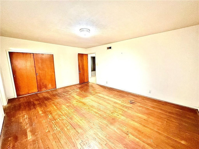 unfurnished bedroom with hardwood / wood-style floors, a textured ceiling, and a closet