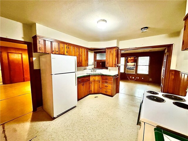 kitchen with a textured ceiling, white appliances, cooling unit, and sink