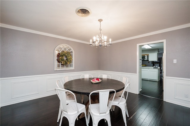 dining room featuring crown molding, dark wood-type flooring, and an inviting chandelier