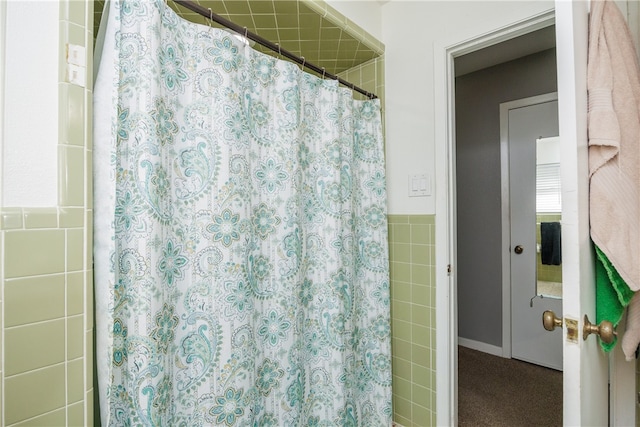 bathroom with a shower with curtain and tile walls