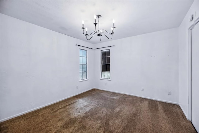 carpeted spare room featuring a chandelier