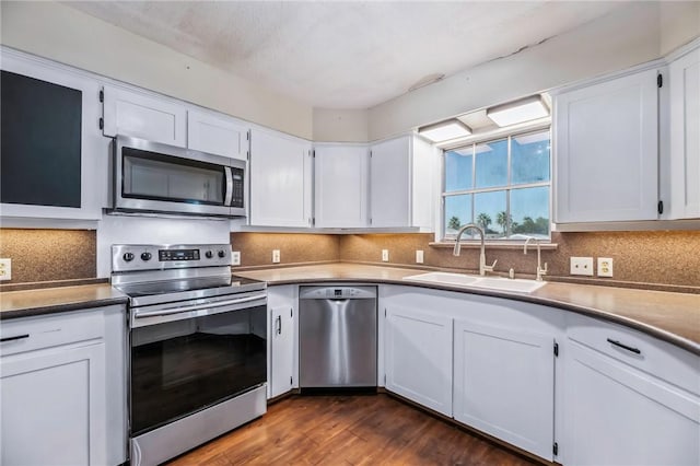 kitchen featuring sink, backsplash, stainless steel appliances, dark hardwood / wood-style floors, and white cabinets