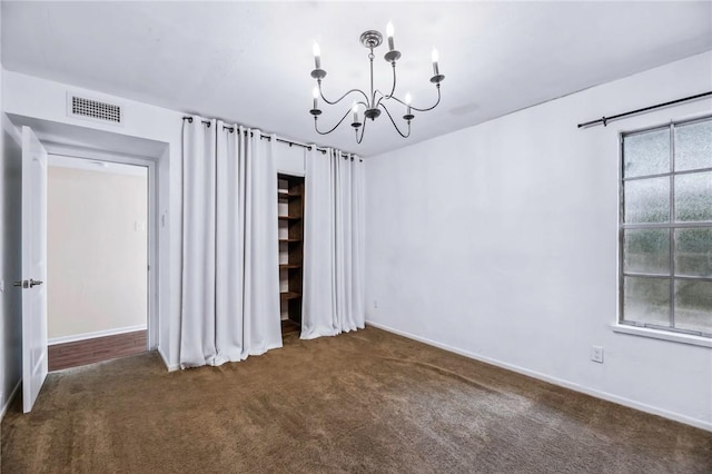 carpeted empty room featuring plenty of natural light and a chandelier