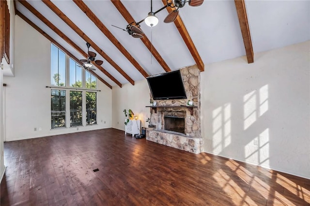 unfurnished living room with a stone fireplace, high vaulted ceiling, hardwood / wood-style flooring, ceiling fan, and beam ceiling