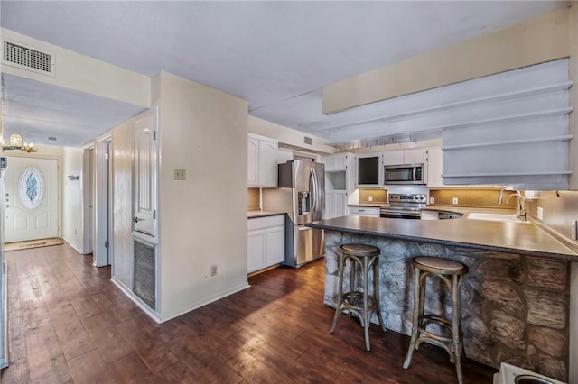 kitchen with white cabinetry, sink, a breakfast bar area, kitchen peninsula, and stainless steel appliances