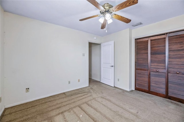 unfurnished bedroom with ceiling fan, light colored carpet, and a closet