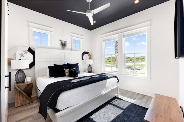 bedroom with ceiling fan, light hardwood / wood-style floors, and multiple windows