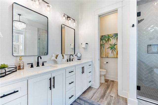 bathroom featuring an enclosed shower, vanity, wood-type flooring, an inviting chandelier, and toilet